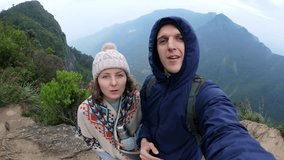 Couple stands on top mountain taking selfie in front stunning landscape. Man and woman capture their moment of triumph climbing with selfie at top.Two hikers taking selfie on top of mountain in Asia. - Powered by Shutterstock - Get 15% off with code: PIKWIZARD15