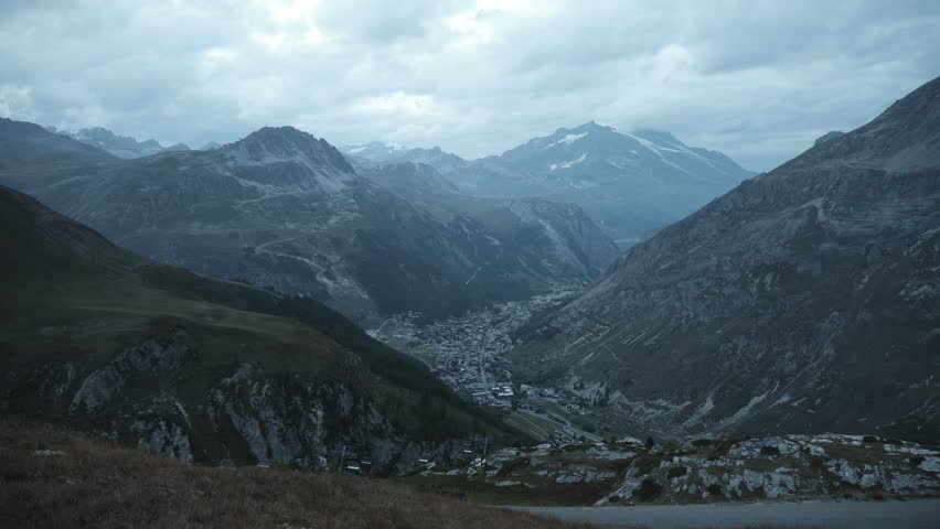 day to night time lapse of clouds moving over the valley of val d isere from top of a mountain in french alps, stage of the tour de france.