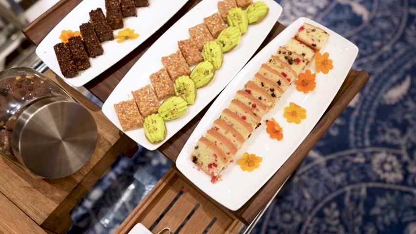 A beautifully decorated catering banquet table with a variety of cakes. Buffet food is set up for corporate event.