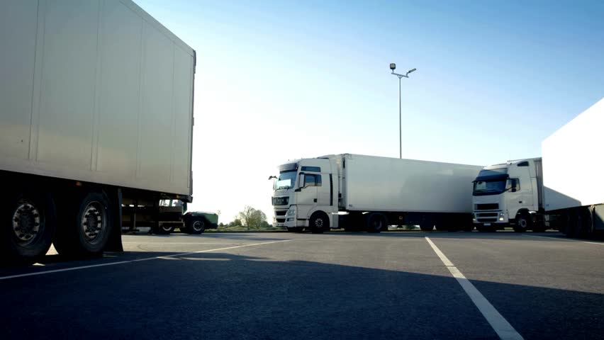 view of a parking lot of large trucks with cargo. Stop for truck drivers. Semi-Trucks with Cargo Trailer parking on the Overnight Parking Place.