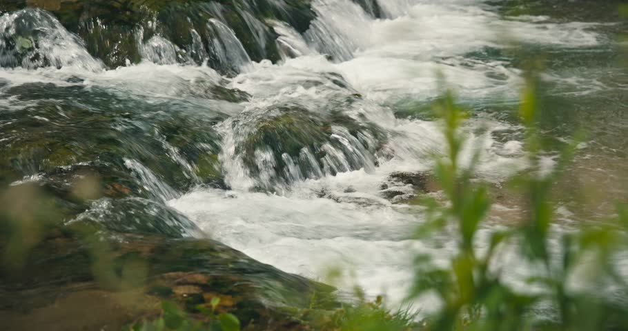 Close-up view of the fast-flowing water over mossy rocks in the Slunjčica River in Rastoke, Croatia.