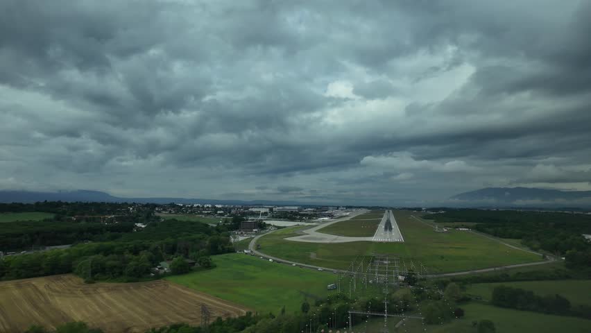Geneve, Switzerland. POV real time runway view shot from an airplane cockpit. Airport surrounded by green ladscape. Stormy grey sky. 4K 60FPS