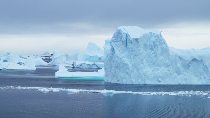 Big Antarctica Iceberg Landscape Sunset, Large Massive Blue Icebergs with Amazing Shapes and Dramatic Couds and Sky in Sunrise Winter Seascape Scenery on Antarctic Peninsula in Icy Scene