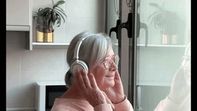 Happy bonding aged senior retired couple embrace near the window enjoying peaceful moment together at home. Elderly woman listening to music with headphones - Powered by Shutterstock - Get 15% off with code: PIKWIZARD15