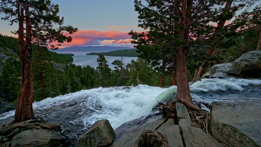 Sunset view of Lower Eagle Falls flowing into Emerald Bay surrounded by pine trees and distant Sierra Nevada mountains at Lake Tahoe, California. 4K UHD video.