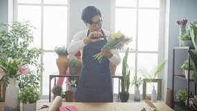 Asian man arranging flowers in a bright, indoor flower shop - Powered by Shutterstock - Get 15% off with code: PIKWIZARD15