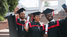 Happy multiracial group of students in graduation dresses and hats taking selfie together - Powered by Shutterstock - Get 15% off with code: PIKWIZARD15