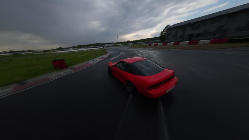 drifting cars on a racetrack of different colors are being pasted on asphalt, a FPV drone is shooting, rubber is smoking, riding sideways