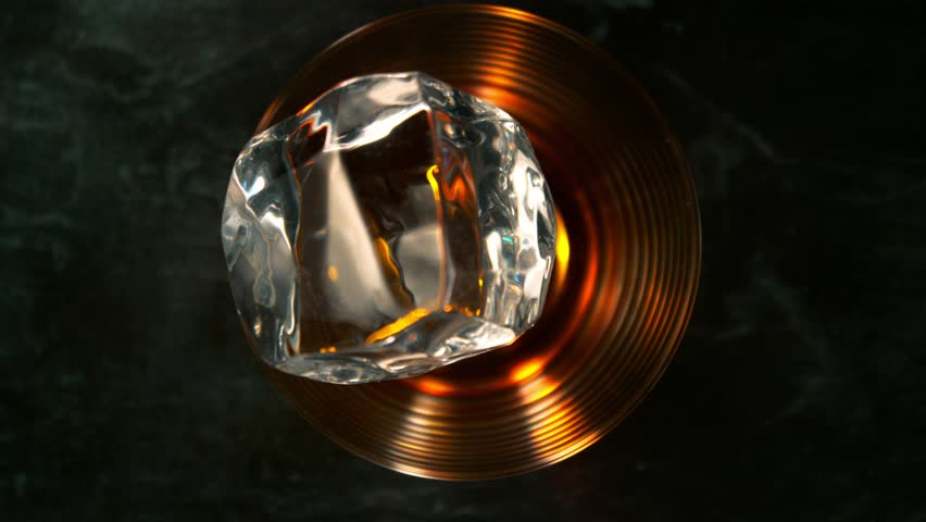 Super Slow Motion Shot of Ice Cube Falling into Glass with Alcohol at 1000fps with Camera Motion.