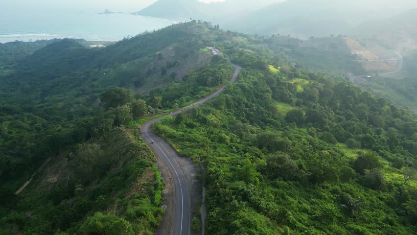 Lombok, Indonesia: Aerial footage of a motorcycle driving in the mountain ridge in southern Lombok in Sekotong area in Indonesia. 