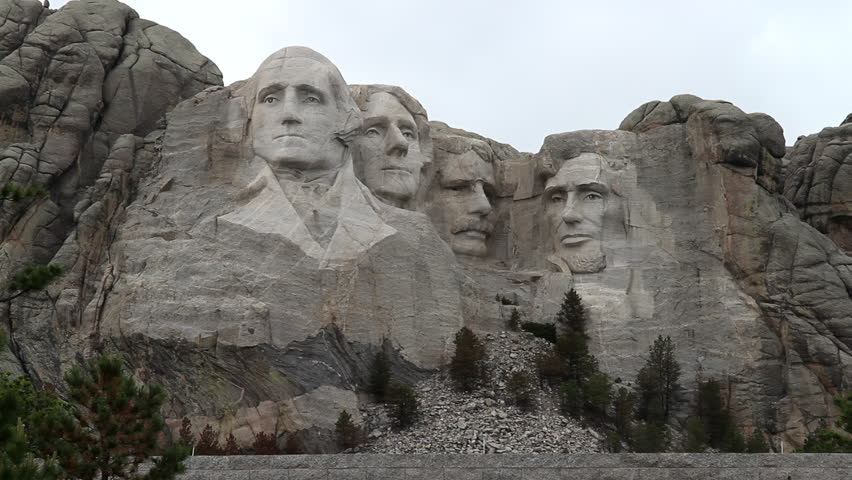 Mount Rushmore on a cloudy day, Black Hills Region of South Dakota. The overcast sky adds a dramatic backdrop to the iconic monument, highlighting the intricately carved faces of four U.S. presidents.