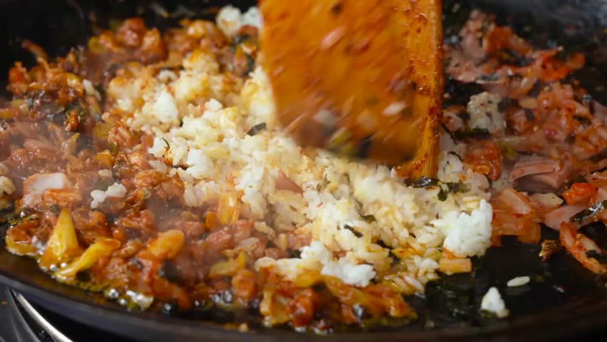A colorful mix of stewed vegetables, rice, nori, and sausage, seasoned with spices and served hot.
