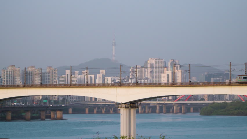 A View Of Train At Dangsan Dong Rail Bridge Towards Yeongdeungpo Market Station In South Korea. Telephoto shot With Seoul Namsan Tower in Background