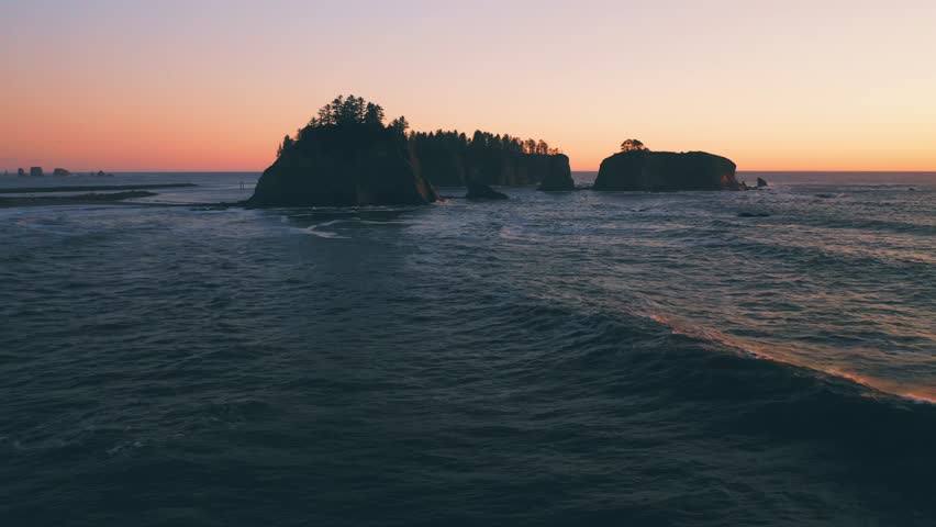 Little James Island at sunset. Dolly in aerial looking over ocean waves at Rialto Beach, Washington Coast, PNW