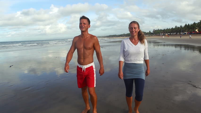 A guy walking with a girl on beach