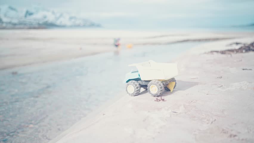 Toy dump truck floats away on a beautiful beach in Northern Norway right outside of Tromso, Norway. With big mountains in the background, a stunning capture. #untraceableglobal