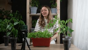 Woman blogger records educative video about seedlings cultivation at home. Happy female gardener shoots video lesson for beginners in workshop