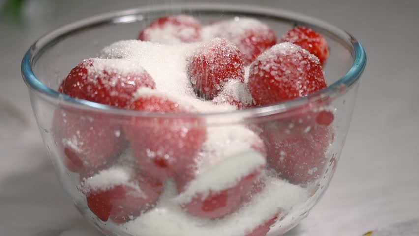 strawberries in a glass bowl and granulated sugar