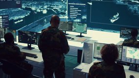 Commander and his crew operating radar systems via CCTV and satellite to detect and track enemy aircraft or missiles. Military officer uses big screen in control center to guarantee safety. Camera B. - Powered by Shutterstock - Get 15% off with code: PIKWIZARD15