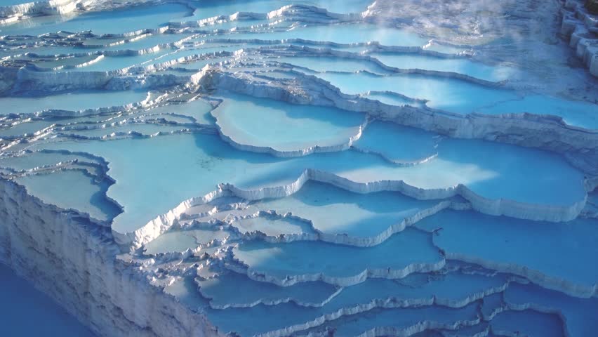 Steamy blue hot springs, mineral waters, forming travertine limestone mineral deposit formations. Breathtaking Landscape: Pamukkale, Turkey (Türkiye) Ancient UNESCO World Heritage Site. Hierapolis. 4K