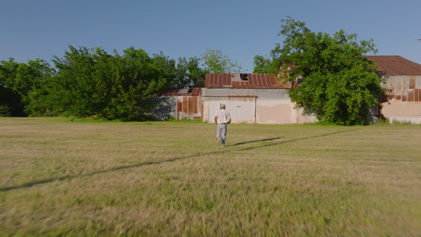 Worker approaches an aged building in the american countryside, set amidst lush greenery and trees in sunny summer day