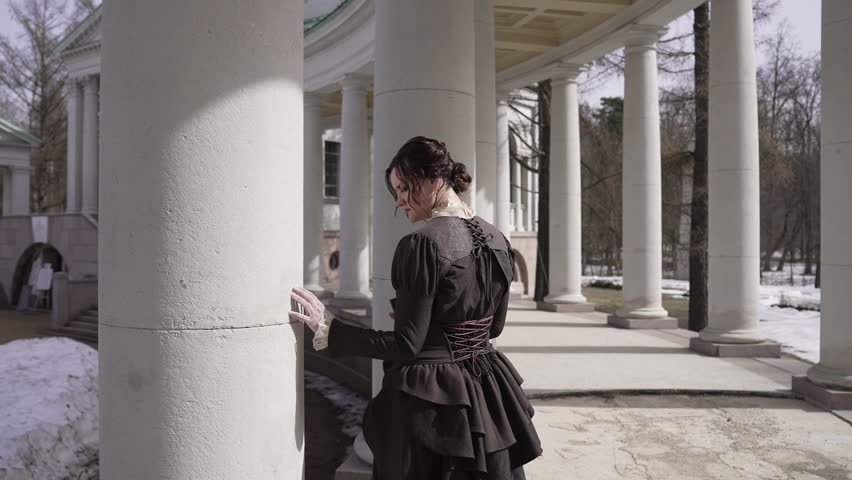Portrait of a Victorian woman in a snowy architectural setting with pillar columns