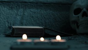 Creepy old worn book with human skull and candle bokeh 4k shot selective focus - Powered by Shutterstock - Get 15% off with code: PIKWIZARD15