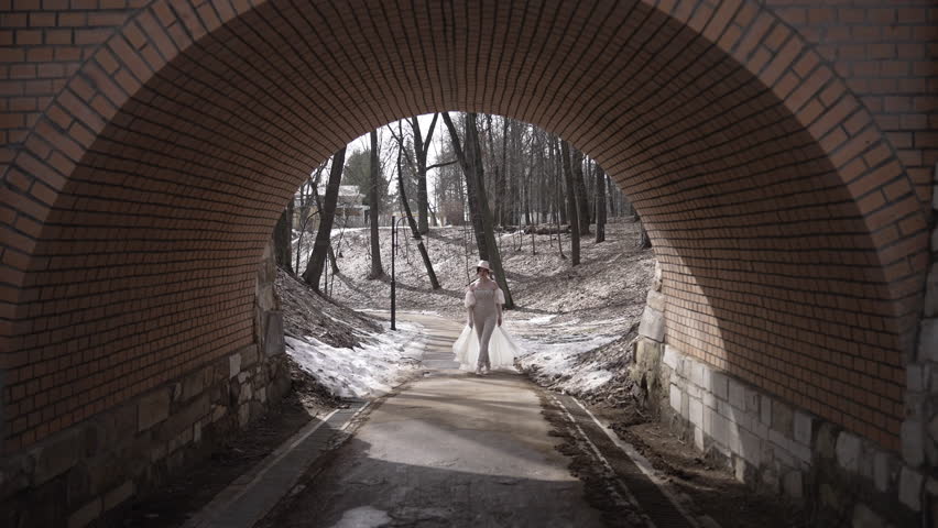 Elegant woman in snowy park tunnel, showcasing style and grace in serene winter setting