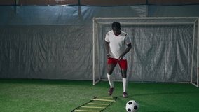Athletic man exercising in sport arena, future African American soccer champion. Professional sport and active pastime for stay healthy. Forward or defender training in football club, artificial grass - Powered by Shutterstock - Get 15% off with code: PIKWIZARD15