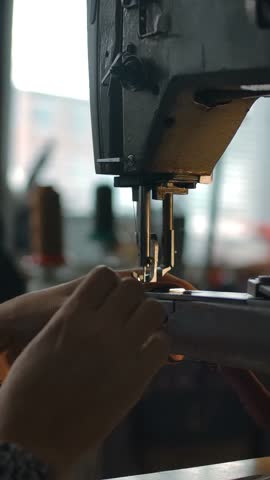 Seamstress working on sewing machine, stitching textile, fabric. Sewing workshop background. Concept for atelier, repairing and tailoring clothes. Handcraft manufacturing. Camera's span Vertical shot.