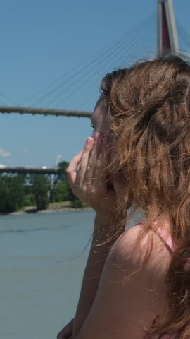 a young girl relaxes on the embankment overlooking the bridge, river, warm sunny summer day. Skytrain Bridge in New Westminster and Surrey, Greater Vancouver, British Columbia, Canada.