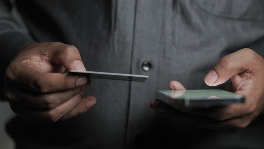 Man shopping online using credit card and smartphone. Businessman holding a mobile phone making a purchase on website or application. Banking, ecommerce, finance, instant digital payment concept.