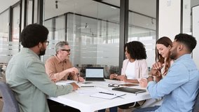 A diverse group of professionals is gathered around a meeting table in a contemporary office space, actively engaged in a productive brainstorming session, looking at laptop screen with graph and talk - Powered by Shutterstock - Get 15% off with code: PIKWIZARD15