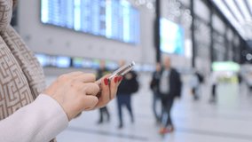At an airport terminal, a woman is using her smartphone to check for flight information on digital boards - Powered by Shutterstock - Get 15% off with code: PIKWIZARD15