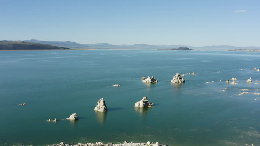 Aerial view of Mono Lake with its distinctive tufa formations rising from the water, surrounded by a vast and serene landscape under a clear blue sky