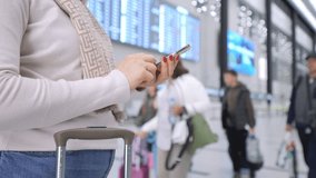 A traveler with a suitcase waits at the airport, using their smartphone before their flight - Powered by Shutterstock - Get 15% off with code: PIKWIZARD15