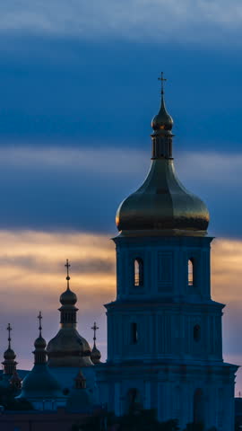 The evening lighting turns on and illuminates the Sofia Bell Tower against the backdrop of beautiful sunset clouds. Kyiv, Ukraine. Vertical video.