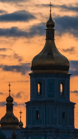 The evening lighting turns on and illuminates the Sofia Bell Tower against the backdrop of beautiful sunset clouds. Kyiv, Ukraine. Vertical video.
