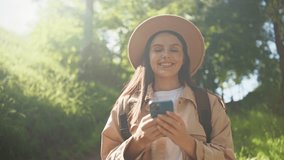 Beautiful Caucasian tourist texting with friends or family on her cell phone. Happy woman smiling with joy while standing in forest while communicating remotely. Concept of technology. - Powered by Shutterstock - Get 15% off with code: PIKWIZARD15