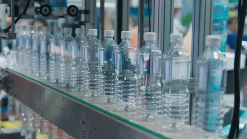 A Row of Clear Plastic Bottles Moving Along a Production Line in a Factory, Ready for Filling. Industrial Manufacturing Process in Action