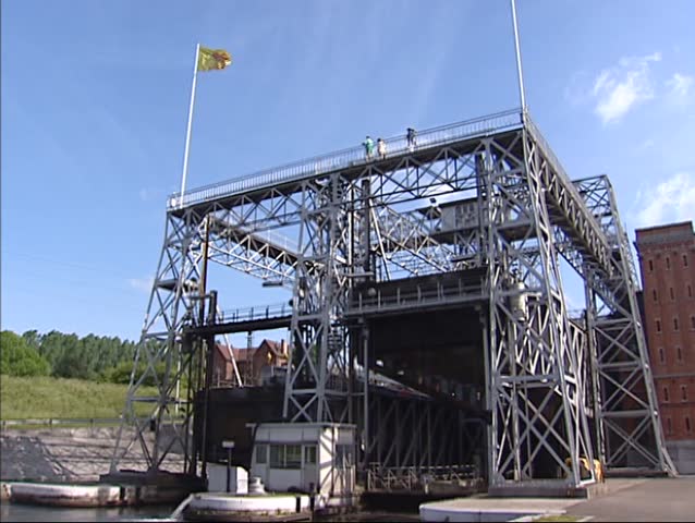 Boat lift in operation with vessel in top container descending, front view. Boat lift no.1 in old Canal du Centre, Houdeng-Goegnies, Belgium,  visitors on top