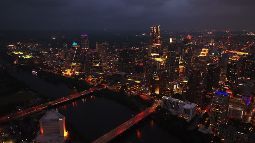 Downtown Austin at night, capturing illuminated bridges and skyscrapers reflecting lights on Colorado river tranquil water
