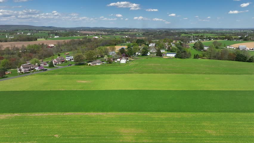Bright green farmland in spring. Aerial truck shot of rural USA farming community.