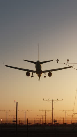 Vertical Screen: View a vertical video of an airplane landing at twilight airport, showcasing the beauty of aviation against a sunset backdrop. See the descent, approach, and touchdown of the aircraft
