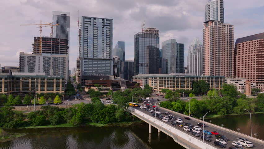 Aerial view of Austin downtown skyline with busy city streets and traffic on the bridge over Colorado River, showcasing the lively urban scene of the Texas capital