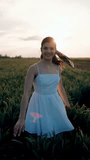 Beautiful woman in a white dress posing and dancing in a green wheat field. Freedom concept. Vertical video