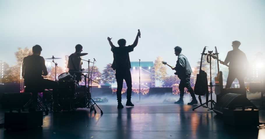 Talented Rock Band Performing a Live Set on Open Air Stage with Fire Pyrotechnics. Young Musicians Playing a Concert at a Festival, Singing Hard Rock Songs at an Indie Event. Back View