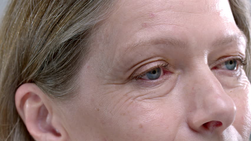 Close-up: eyes of an old woman macro. Senior female smiles and laughs, wrinkles near the eyes. Happy Lady enjoying happy active life, aging. Old skin of wrinkled face of Caucasian. Beauty portrait