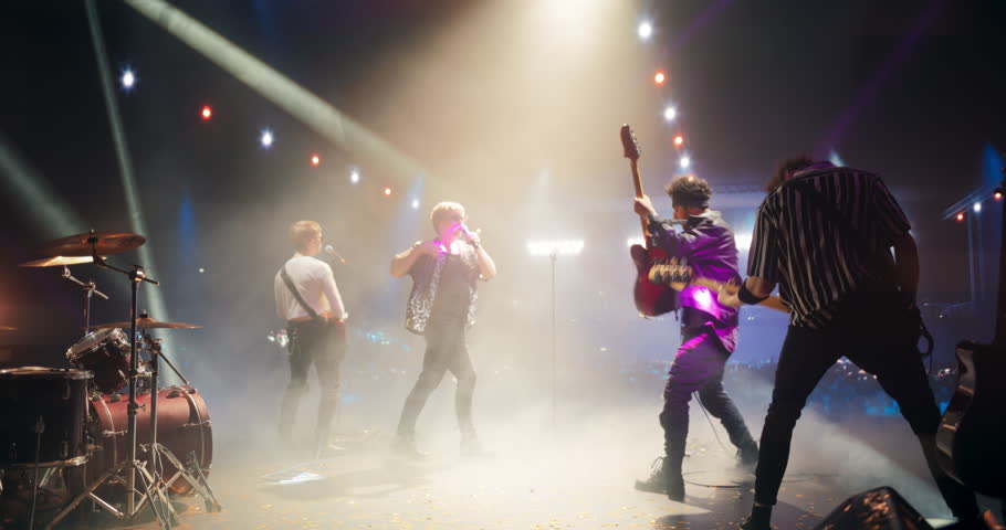 Rock Musicians in Fashionable Outfits Performing Alternative Punk Rock Music on a Nightclub Stage, Passionately Playing Guitars Under Bright Spotlights, Bringing Energy to Cheering Fans