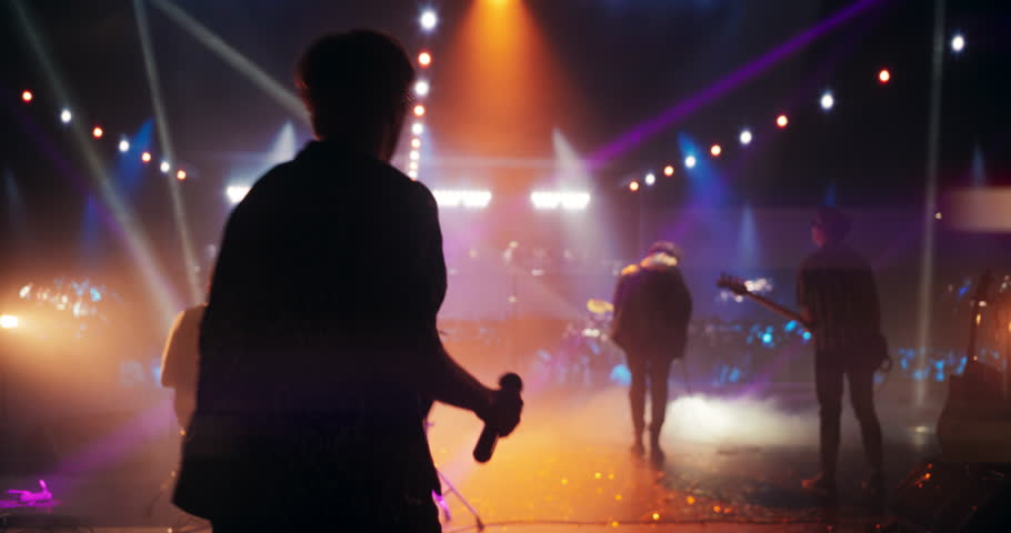 Band Playing Hit Songs on Electric Guitars and Drums. Young Rock Musicians Performing a Live Concert, Dancing, Having Fun, Entertaining a Crowd of Rock Music Fans at an Alternative Festival